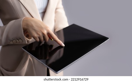 Businesswoman Using Tablet Finger Pointing And Touching On Blank Black Tablet Screen Grey Background. Business And Technology Concept.