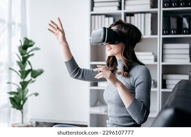 Businesswoman with vr headset lifestyle concept, Businesswoman wearing VR headset to playing game and touching in the air for experience virtual reality while relaxation with technology after working. - Powered by Shutterstock