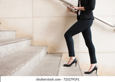 Businesswoman walking upstairs and using touchpad