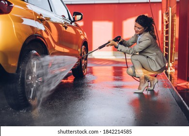 Businesswoman washing car at car wash station using high pressure water machine. - Powered by Shutterstock