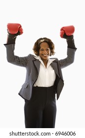 Businesswoman Wearing Boxing Gloves Holding Arms Up In Victory Stance And Smiling.