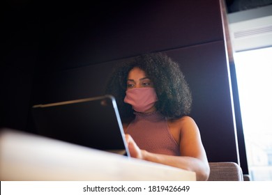 Businesswoman Wearing Mask Working In Socially Distanced Cubicle In Office During Health Pandemic