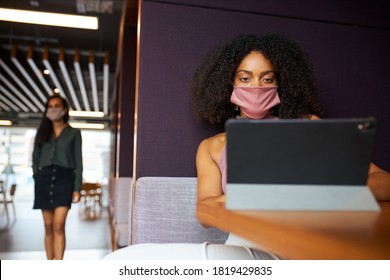 Businesswoman Wearing Mask Working In Socially Distanced Cubicle In Office During Health Pandemic