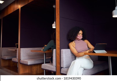 Businesswoman Wearing Mask Working In Socially Distanced Cubicle In Office During Health Pandemic