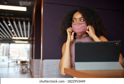 Businesswoman Wearing Mask Working In Socially Distanced Cubicle In Office During Health Pandemic