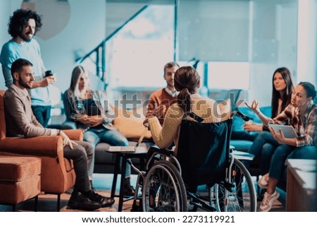 Businesswoman in wheelchair having business meeting with team at modern office. A group of young freelancers agree on new online business projects