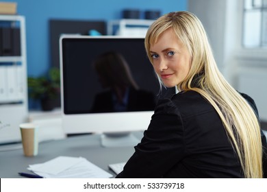 Businesswoman Working With Computer In The Office Looking Back Over Her Shoulder With A Smile