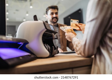 Businesswoman is working in exchange office. She is giving cash money to male customer. - Powered by Shutterstock