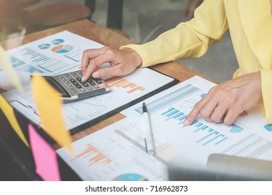 Businesswoman working at his coffee shop and using laptop, discussing the charts and graphs showing the results of their successful. - Shutterstock ID 716962873