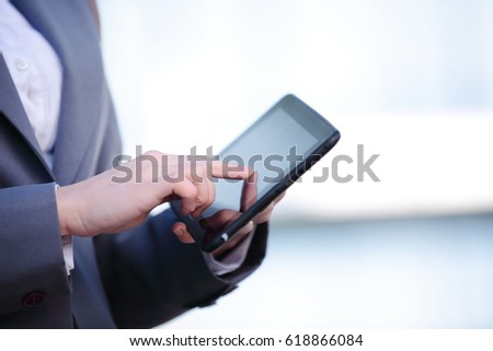 Businesswoman working on digital tablet outdoor over modern building background