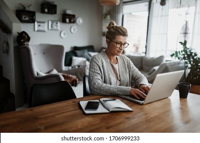 Businesswoman working on laptop computer sitting at home and managing her business via home office during Coronavirus or Covid-19 quarantine