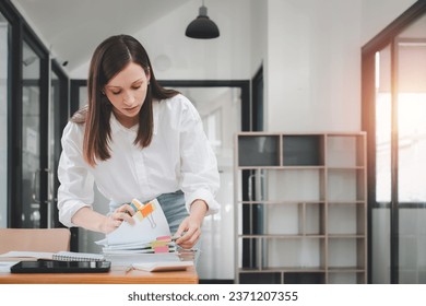 Businesswoman working in Stacks of paper files for searching and checking unfinished document achieves on folders papers at busy work desk office	 - Shutterstock ID 2371207355