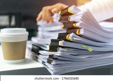 Businesswoman working in stacks of paperwork files for searching infomation unfinished documents about pile audit form on desk office near paper coffee cup and work financial doc in busy workload