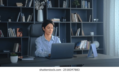 Businesswoman works from her home office, focused on her laptop, surrounded by a professional atmosphere - Powered by Shutterstock