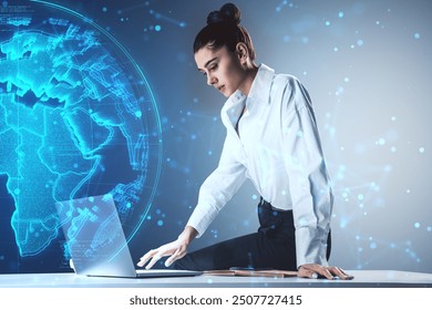 A businesswoman works on a laptop, with a virtual globe hologram and digital network lines in the background. Concept of global communication and technology - Powered by Shutterstock