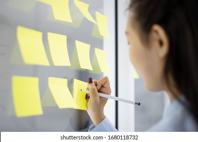 businesswoman write short note to do list in  sticker on glass in meeting office room, focus on woman's hand