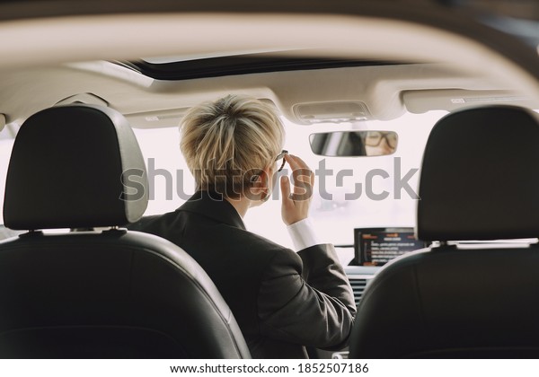 Businesswomanin a car. Lady\
in a black\
suit.