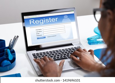 Businesswoman's Hand Filing Online Registration Form On Laptop In Office