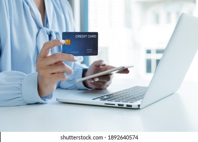 The businesswoman's hand is holding a credit card and using a smartphone for online shopping and internet payment.