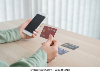 The businesswoman's hand is holding a credit card and using a smartphone for online shopping and internet payment in the office.