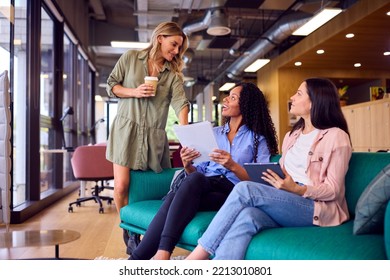 Businesswomen Having Informal Meeting In Breakout Seating Area Of Modern Office