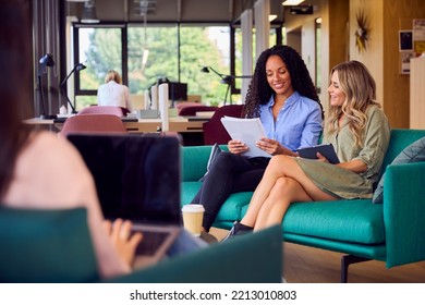 Businesswomen Having Informal Meeting In Breakout Seating Area Of Modern Office