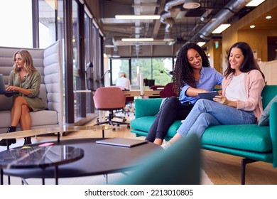 Businesswomen Having Informal Meeting In Breakout Seating Area Of Modern Office