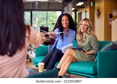 Businesswomen Having Informal Meeting In Breakout Seating Area Of Modern Office