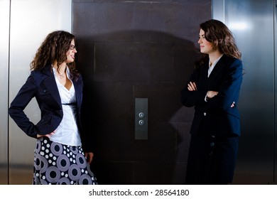  Businesswomen Waiting For Elevator At Office And Talking.