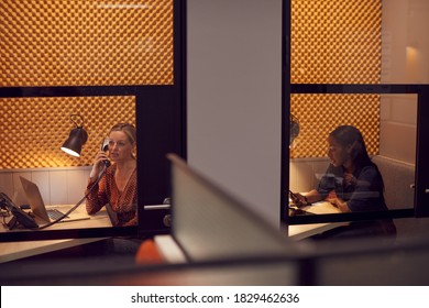 Businesswomen Working Late In Individual Office Cubicles Using Laptop And Digital Tablet