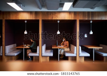 Businesswomen Working In Socially Distanced Cubicles In Modern Office During Health Pandemic