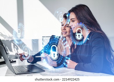 Businesswomen working together finger pointing at laptop on desk, smiling portraits. Glowing padlock icon with circuit hud. Cybersecurity and data protection. Concept of network