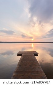 Busnieku Lake At Sunset. Ventspils, Latvia. Wooden Pier. Soft Sunlight, Glowing Clouds, Symmetry Reflections In A Crystal Clear Water. Spring, Early Summer. Panoramic View. Nature, Ecology, Ecotourism