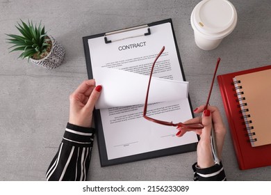 Busniesswoman Looking And Reading Contract At The Desk In Office. Young Woman Reviewing A Contract Before Signing It.