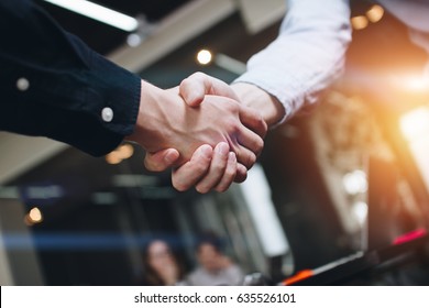 Bussines partners handshakes in modern open space on the background of coworking team on new startup project - Shutterstock ID 635526101