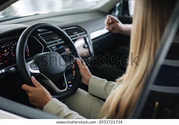 Bussines woman choosing car i\
car showroom. Salesperson sitting in car with customer and show\
desing