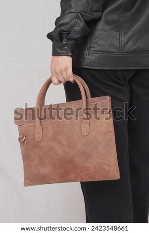 a bussiness woman posing in black leather jacket and brown leather bag 