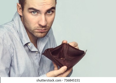 Bussinessman holding an empty wallet in his hands. The guy shows the lack of money