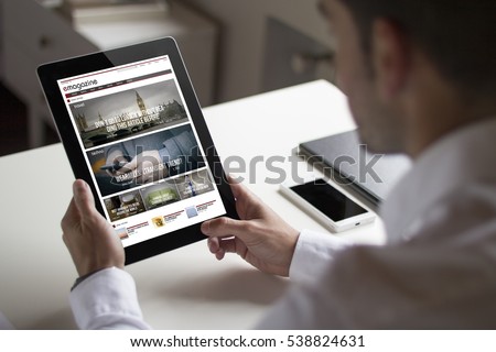 bussinessman at office holding a tablet showing magazine website. All screen graphics are made up.