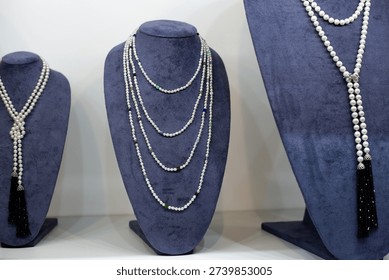 Bust model with expensive beads and multiple lines of jewelry. Jewelry store shelf with pedestals for example wearing precious necklace. Women breast jewelry