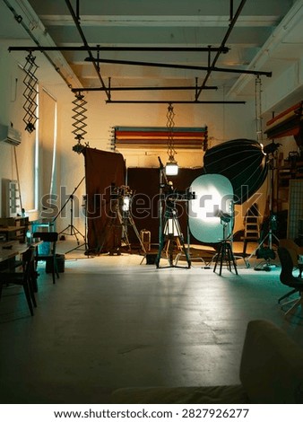 A bustling creative studio showcases a range of professional lighting setups and equipment, ready for an energetic photo shoot. Equipment is arranged thoughtfully, inviting inspiration.