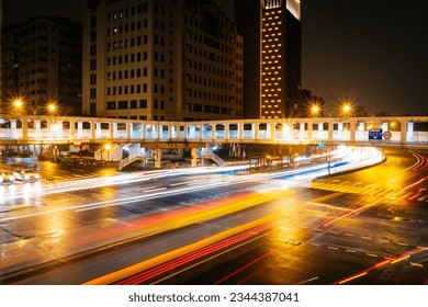 The bustling intersection with heavy traffic makes the city particularly lively, especially the rain-washed ground reflecting bright lights.
