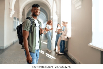 In a bustling university corridor, a young male student with a backpack appears joyful, contrasting with focused classmates in the background, reflecting a dynamic college environment - Powered by Shutterstock