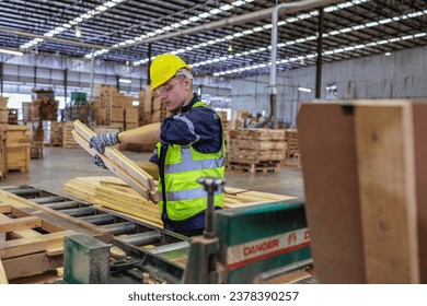 In a bustling warehouse, a Caucasian worker attentively examines a piece of lumber. Dressed in safety gear, he ensures quality amidst stacks of wood, demonstrating diligence in every detail. - Powered by Shutterstock