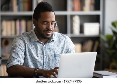 Busy African Man Freelancer Using Modern Professional App Do Remote Work Seated At Desk Homeoffice Cozy Room. Employee Working Typing Business E-mail. E-business, E-learning, E-commerce User Concept