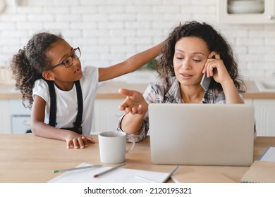 Busy african-american mother mom freelancer working from home on maternity leave trying to concentrate while naughty daughter distracting disturbing her at home. Homeschool and e-learning