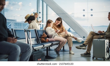 Busy Airport Airplane Terminal: Happy Beautiful Mother and Cute Little Daughter Wait for their Vacation Flight, Use Mobile Smartphone for Fun. Diverse Group of People in Boarding Lounge of Airline Hub - Shutterstock ID 2137645133