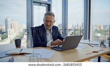 Busy analyst working computer looking papers at corporate workspace closeup. Elderly businessman writing notes creating investment project in office. Tensed manager solving hard issues making decision