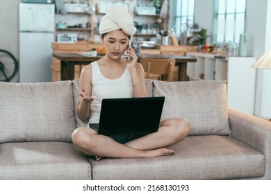 Busy Asian Female Ceo Just Took Bath Is Teleworking In Living Room. Taiwanese Woman Is Having Business Talk On Phone While Looking At Data On Computer. Work From Home Concept