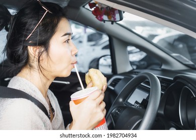 Busy Asian Woman Eating Fast Food And Drink Coffee In Car 